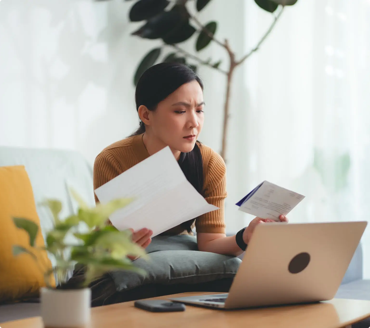 Woman checking paperwork and laptop